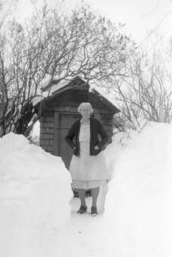 Blanch (Sampson) Lawson standing by out-house in winter - circa unknown