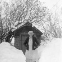 Blanch (Sampson) Lawson standing by out-house in winter - circa unknown